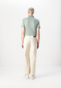 Světlý zelený polo triko a krémové kalhoty se rovný fit. Hladká textura, minimalistický design a jemné detaily šití.