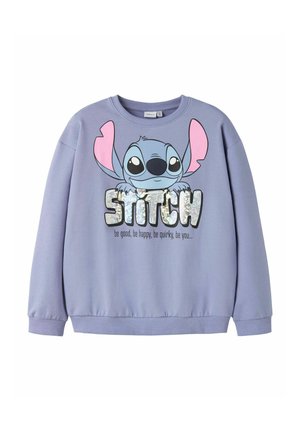 Sweatshirt lavande avec un grand dessin animé de Stitch tenant un texte pailleté "STITCH" et la devise "sois bon, sois heureux, sois original, sois toi" en dessous.