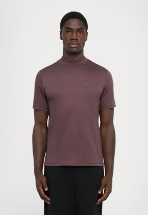 Kortærmet skjorte i dæmpet mauve, fremstillet af blødt stof med høj halsdesign. Har et minimalistisk logo på brystet og en glat tekstur.