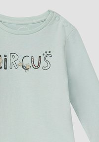 Himmelblaues Langarmshirt mit "CIRCUS" in gemusterten Buchstaben, Tiergrafiken und Druckknöpfen an der Schulter für einfaches Anziehen.