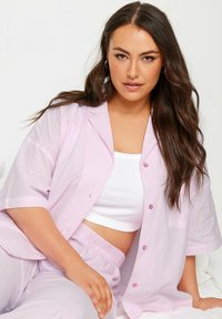 Vaatekokoelma vaaleanpunaisista raidallisista pyjamaseteistä, jotka on valmistettu kevyestä kankaasta; lyhythihainen napitettava paita, jossa on tasku, yhdistettynä joustavyöshortseihin.