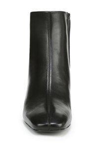 Bottine en cuir noir avec un bout arrondi et une texture lisse. Présente une fermeture éclair sur le côté et des détails de couture verticale sur l'avant.