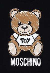 Grafica di un orsetto di peluche marrone con una maglietta bianca che recita "Giocattolo" su uno sfondo nero, con contorni audaci e dettagli in stile schizzo giocoso.