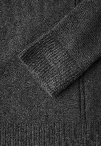Mörkgrått stickat tröjfoder med en ribbad manschett och en mjuk, texturerad yta. Har släta sömmar och en klassisk design.