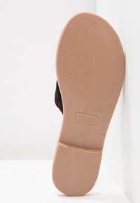 Black shoe bottom view featuring a smooth, light brown sole with ridges and embossed brand name "ANNA FIELD" along with size "37."