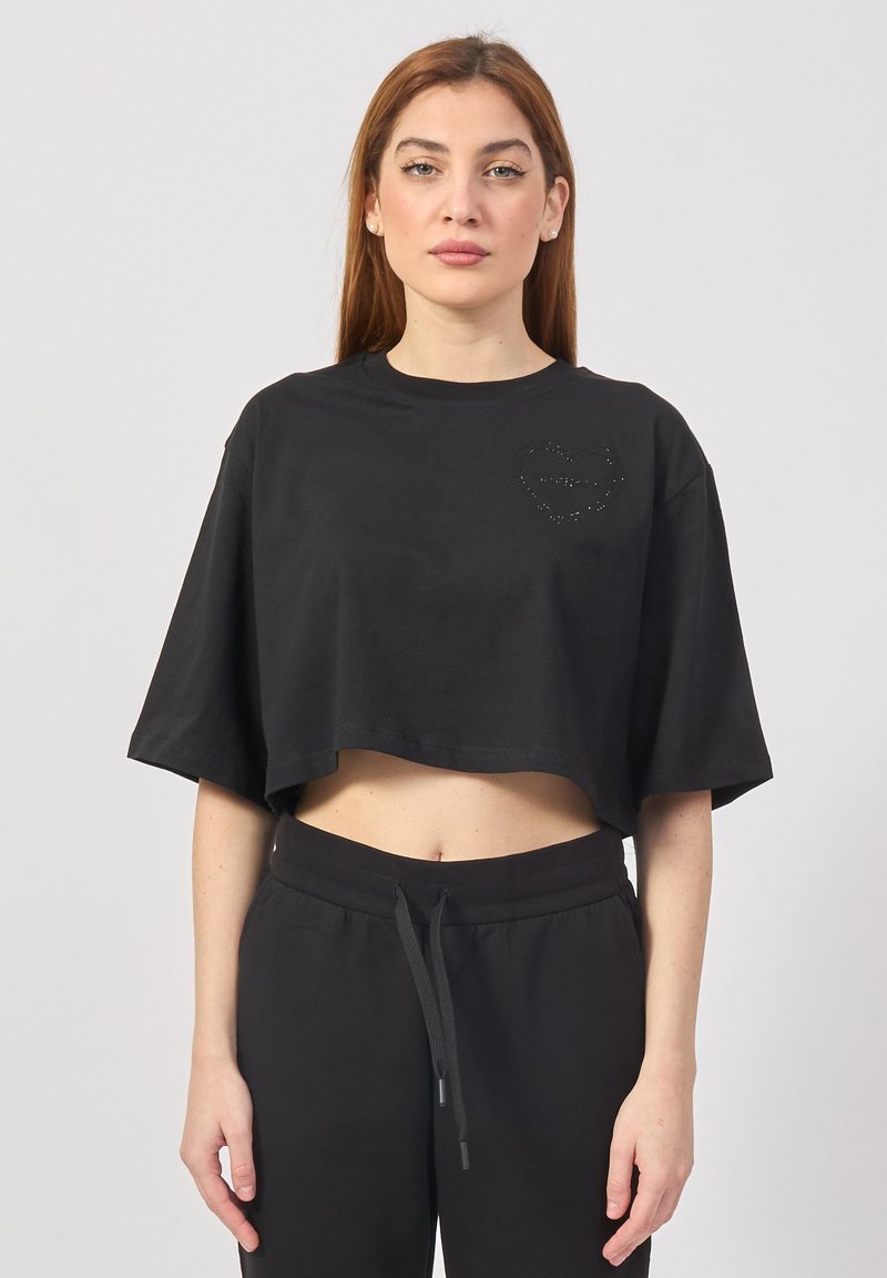 T-shirt cropped nero realizzato in morbido cotone, con scollo rotondo e maniche corte, decorato con un design a forma di cuore delineato da strass.