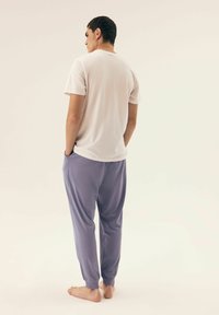 White cotton t-shirt, short sleeves, rounded neckline; paired with lavender jogger pants, side pockets, elastic cuffs, relaxed fit.