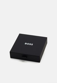 Boîte noire avec un tiroir amovible, arborant le texte blanc "BOSS" sur le dessus. Fini mat lisse, forme rectangulaire, design épuré.
