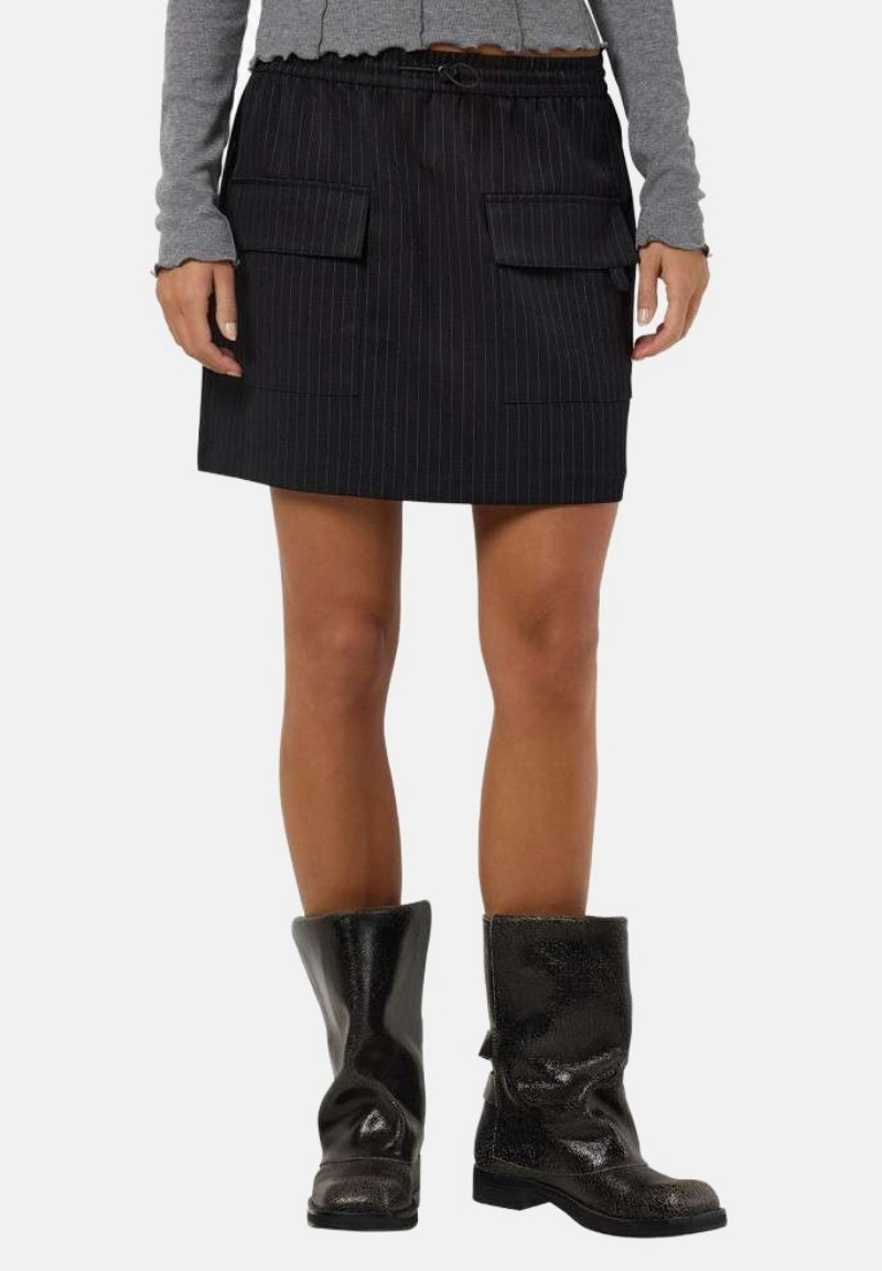 Jupe noire à rayures avec une taille élastique, dotée de deux poches avant. Associée à des bottes noires brillantes jusqu'au genou.