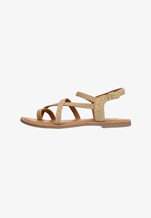 Tan strappy sandals with woven texture, flat rubber sole, adjustable ankle strap, and cross-band design.