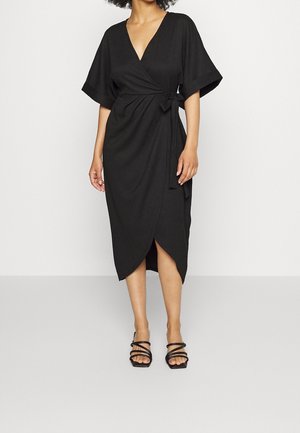 Czarna sukienka o kroju wrap z krótkimi rękawami kimono, dekoltem w serek, przewiązywana w talii i z wysokim rozcięciem. Stylizowana z czarnymi sandałami na ramiączkach.