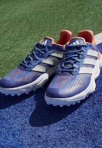 Le scarpe da ginnastica blu presentano una tomaia in mesh testurizzato con accenti rosa, il logo bianco a tre strisce e una suola bianca ammortizzata.