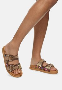 Sandales en cuir marron avec double boucle, empeigne texturée ornée d'accents en perles multicolores et semelle épaisse beige.