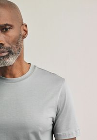 Grijs T-shirt met korte mouwen van zachte stof met een ronde hals. Kenmerkt zich door minimale stiksels en een gladde textuur.