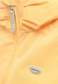 Tessuto di giacca gialla con primo piano della cerniera e una piccola toppa bianca con il logo e la scritta "raqwear."