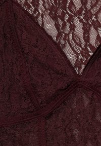 Sötétlila csipke anyag virágmintákkal és hálós panelek, amelyek kereszteződő varrásokat és finom textúrát mutatnak.