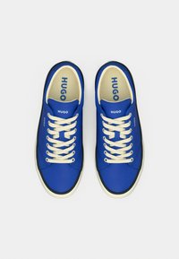 Μπλε πάνινα αθλητικά παπούτσια με κρέμ κορδόνια, στρογγυλή μύτη και μαύρη καουτσούκ σόλα. Λογότυπο "HUGO" στη γλώσσα και στο πλάι, με ομαλή υφή.