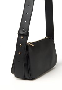 Borsa a spalla in pelle nera con forma rettangolare, cerniera dorata e tracolla regolabile con dettagli borchiati. Texture liscia.