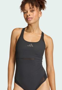 Čierny športový plavky s výstrihom do lode, sieťovými akcentmi a priliehavým strihom. Obsahuje detailné logo v tonálnej úprave a hladký materiál.