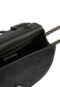 Borsa a tracolla in pelle nera con morbidi dettagli in pelliccia testurizzata. Presenta una tracolla a catena e una chiusura con zip. All'interno ci sono scomparti per carte e un design elegante.