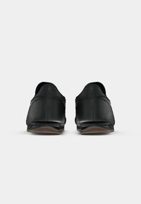 Black leather dress shoes shown from the back on a plain white background, featuring low heels and subtle stitching details.