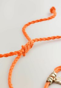Oranž koonusnöör keskel sõlmega ja metallklambriga. Tekstuur näeb välja robustne ja värv on elav ja ühtlane.