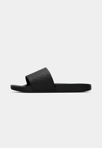 Infradito neri con una parte superiore testurizzata caratterizzata da un motivo circolare, suola in gomma piatta e design open toe.