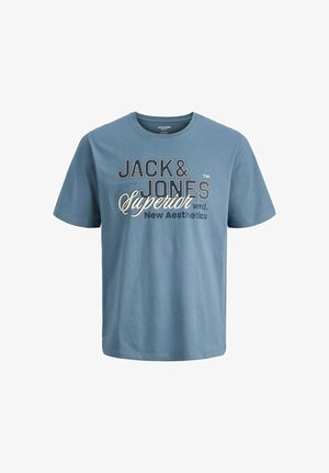 Felpa con cappuccio azzurro chiaro con zip e tasche frontali, indossata sopra una t-shirt grafica blu scuro, abbinata a jeans in denim scuro a gamba larga e sneakers grigie.