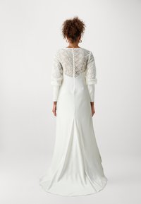 Witte jurk met lange mouwen en een kanten rug, voorzien van een knoopsluiting en een vloeiende sleep. Gladde satijnen textuur, aansluitende silhouet.