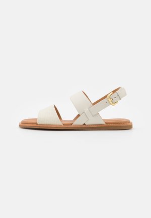 White leather sandals featuring wide straps, a textured design, adjustable ankle strap with gold hardware, and a light brown sole.