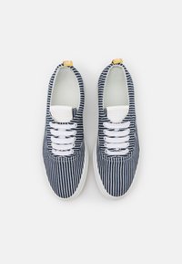 Námořnické a bílé pruhované plátěné tenisky s bílými tkaničkami, lehkou podešví a kontrastním žlutým záložním dílem. Hladký povrch, klasický design.