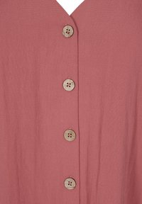 Haut en tissu rose avec un décolleté en V, cinq boutons en bois avec un motif floral et une texture douce et lisse.