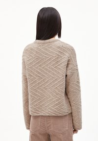 Beige Pullover mit einem strukturierten Fischgrätenmuster, runder Ausschnitt und lockerer Passform. Der Stoff wirkt weich und warm.