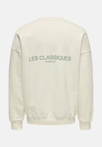Cremefarbener Sweatshirt mit gerippten Bündchen und Saum. "LES CLASSIQUES" und "ORIGINAUX" in gedämpftem Grün auf dem Rücken bedruckt. Weiche Textur.