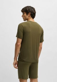Olijfgroen sportoutfit bestaande uit een T-shirt met korte mouwen en shorts, gemaakt van een soepel, rekbaar materiaal met een ontspannen pasvorm.