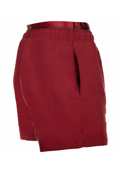 Pantalones cortos rojos para hombre con cintura elástica y bolsillos laterales, mostrando una vista parcial con un forro interior de cintura con marca.