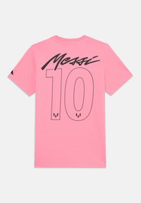 Rosa bomulls t-skjorte med "Messi" og "10" i stor svart skrift på ryggen, med detaljerte logoer nær den nedre kanten. Korte ermer.
