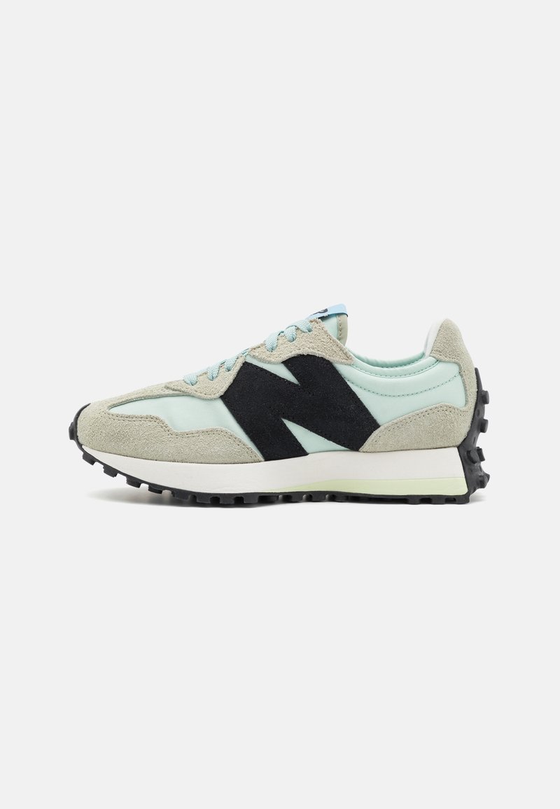 Baskets bleu clair et beige avec un grand logo "N" noir, semelle crantée noire et lacets bleu clair, vue de côté sur fond blanc.