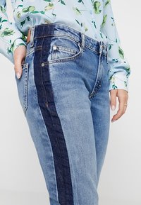 Jeans i denim med en ljusblå tvätt som har en mörkblå sidremsa, fem fickor och en klassisk midja.