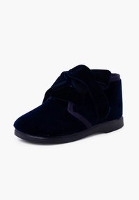 Bottine en velours bleu marine avec un grand nœud décoratif et une semelle noire, conçue pour le confort et le style.
