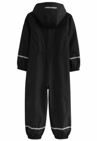 Mono impermeable negro con capucha, cinturilla elástica y franjas reflectantes en las mangas y las piernas. Cuenta con puños elásticos para un ajuste ceñido.