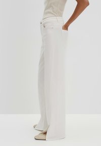 White wide-leg pants with a high waist, featuring front pockets and side slits at the hem. Made of smooth, textured fabric.