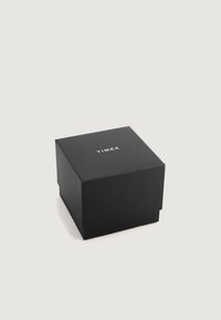 Kvadratna crna kutija s mat površinom i bijelim logotipom "TIMEX" na vrhu. Kutija ima poklopac koji čvrsto pristaje uz dno.