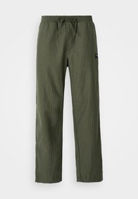 Pantalons à carreaux verts avec une taille élastique, un cordon de serrage ajustable et une petite étiquette en tissu sur le côté. Texture lisse.