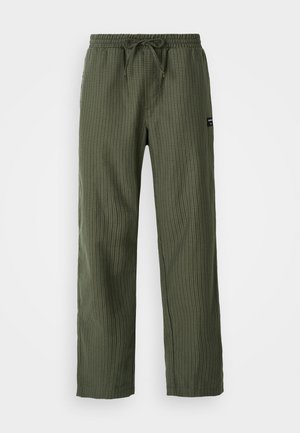 Grüne karierte Hose mit einem elastischen Bund, verstellbarem Kordelzug und einem kleinen Stofflabel an der Seite. Glatte Textur.