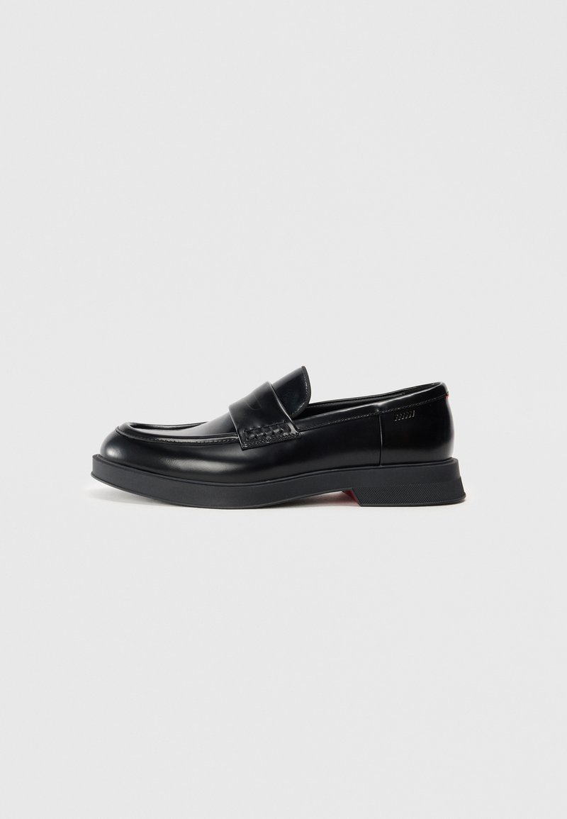 Mustad nahast loafers sileda pinnaga, millel on kõrgendatud esipaneel ja kontrastne punane aktsent tallal. Lame kummist tald.