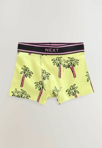 Shorts de boxeur jaunes avec un motif de palmier en noir et rose. Ceinture noire avec le logo "NEXT" en rose. Texture de tissu lisse.