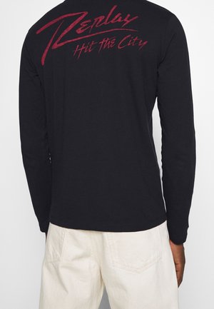 Langärmliges schwarzes T-Shirt mit einem roten "Replay Hit the City"-Grafik auf der Rückseite. Weicher Stoff mit einer normalen Passform und rundem Halsausschnitt.