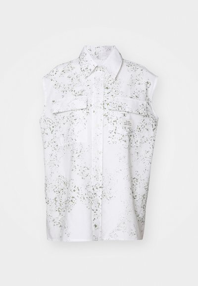 Camicia bianca a maniche corte con motivo a macchie verdi, chiusura frontale con bottoni e due tasche sul petto. Etichetta visibile di lato.