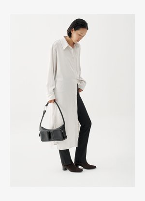 White long button-up shirt, black fitted pants, black leather handbag with dual pockets, and dark brown heeled ankle boots.